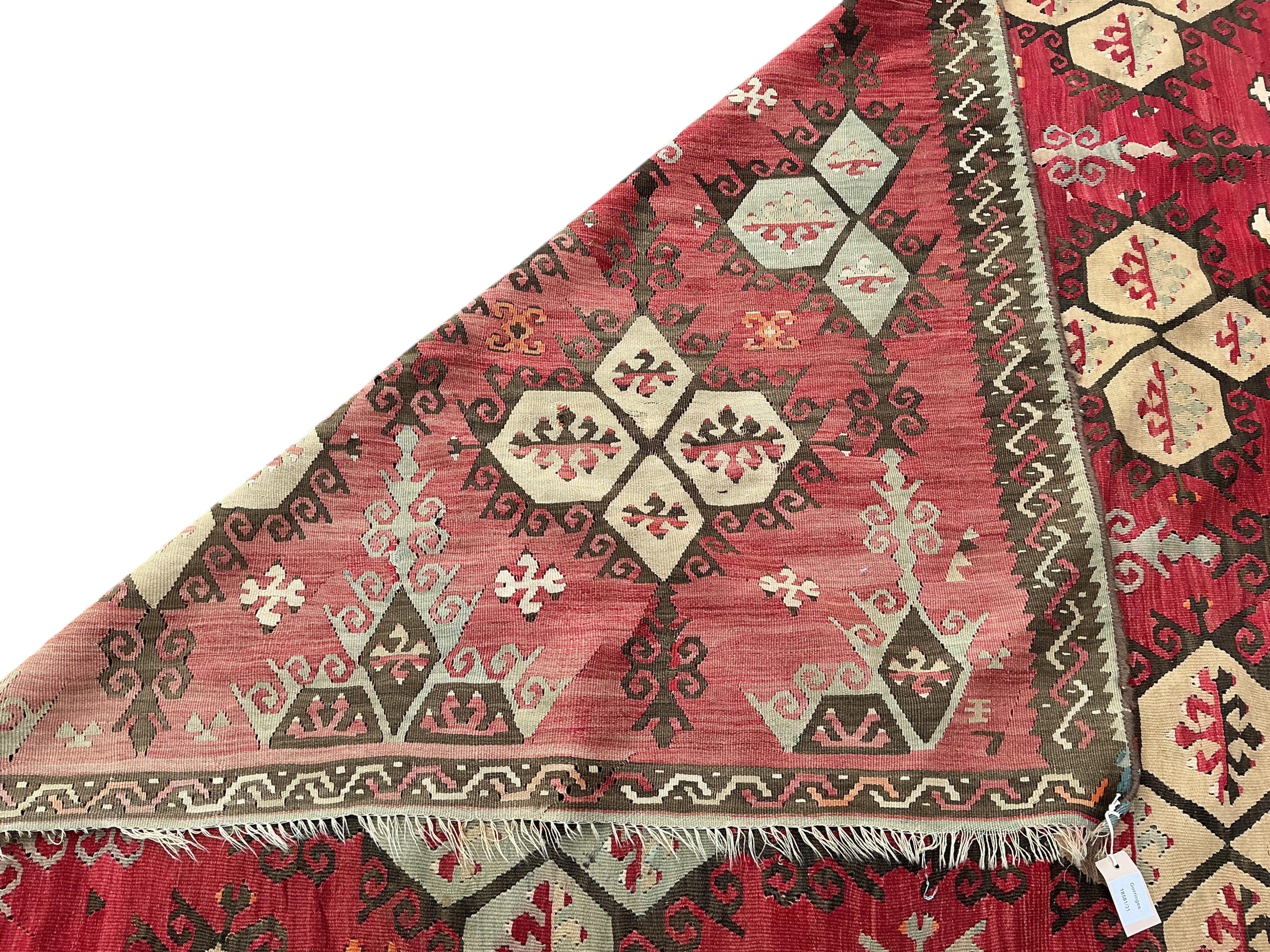 A Turkish Anatolian Kilim polychrome flatweave carpet, woven with geometric lozenges, on a pink field, 350 x 273cm
